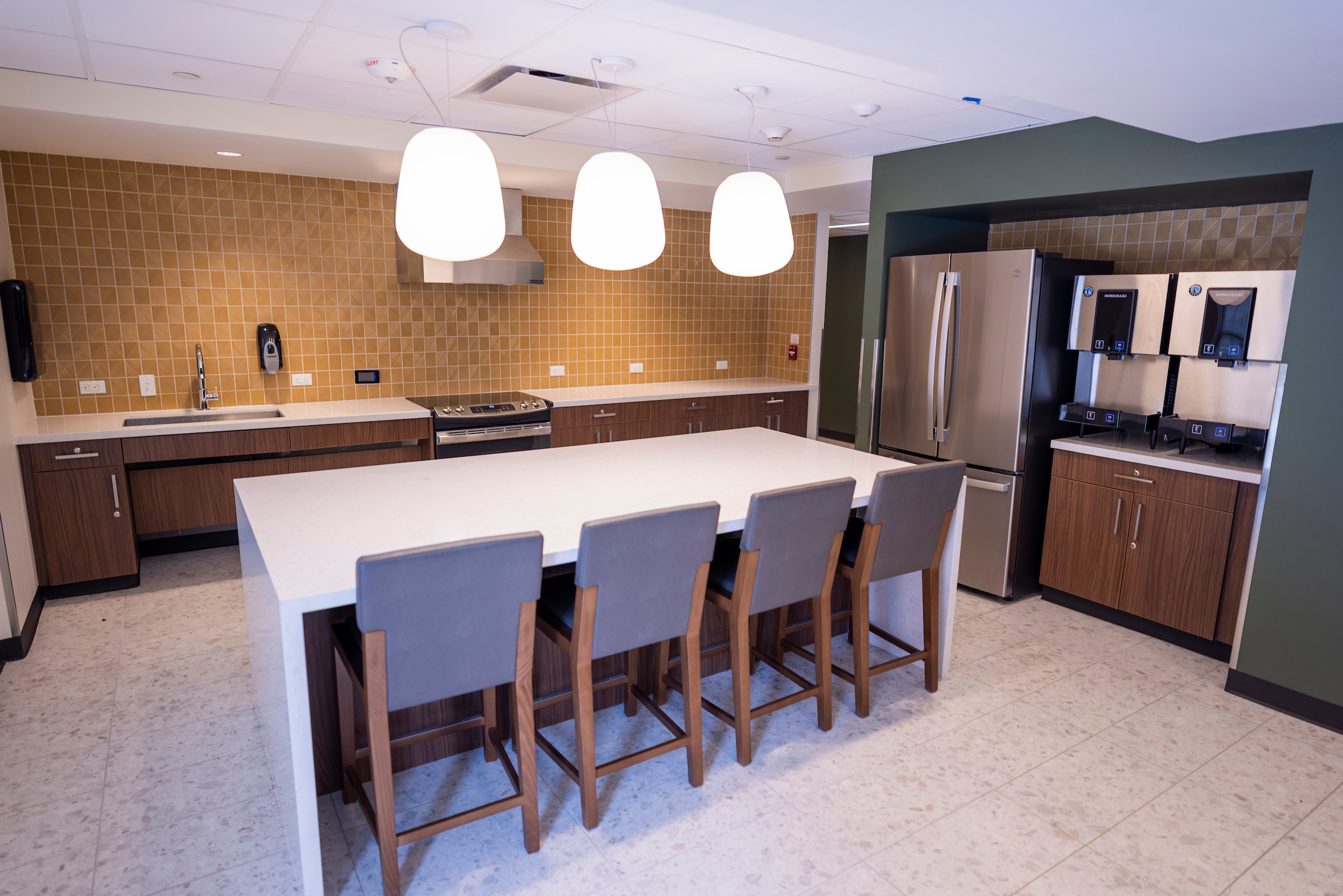 Commons Community Kitchen with yellow tile, an island, oven, and more