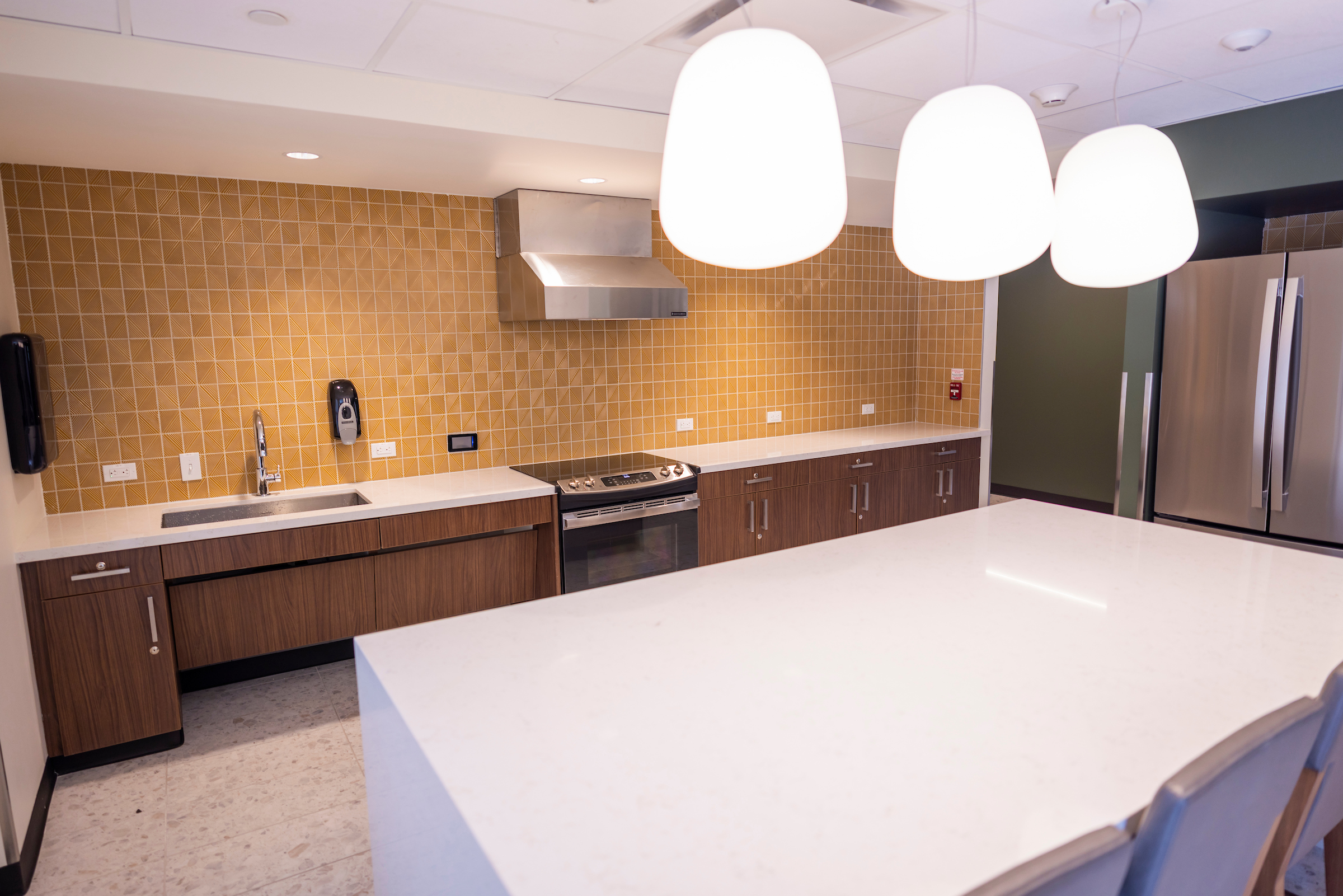 Commons Community Kitchen with yellow tile, an island, oven, and more
