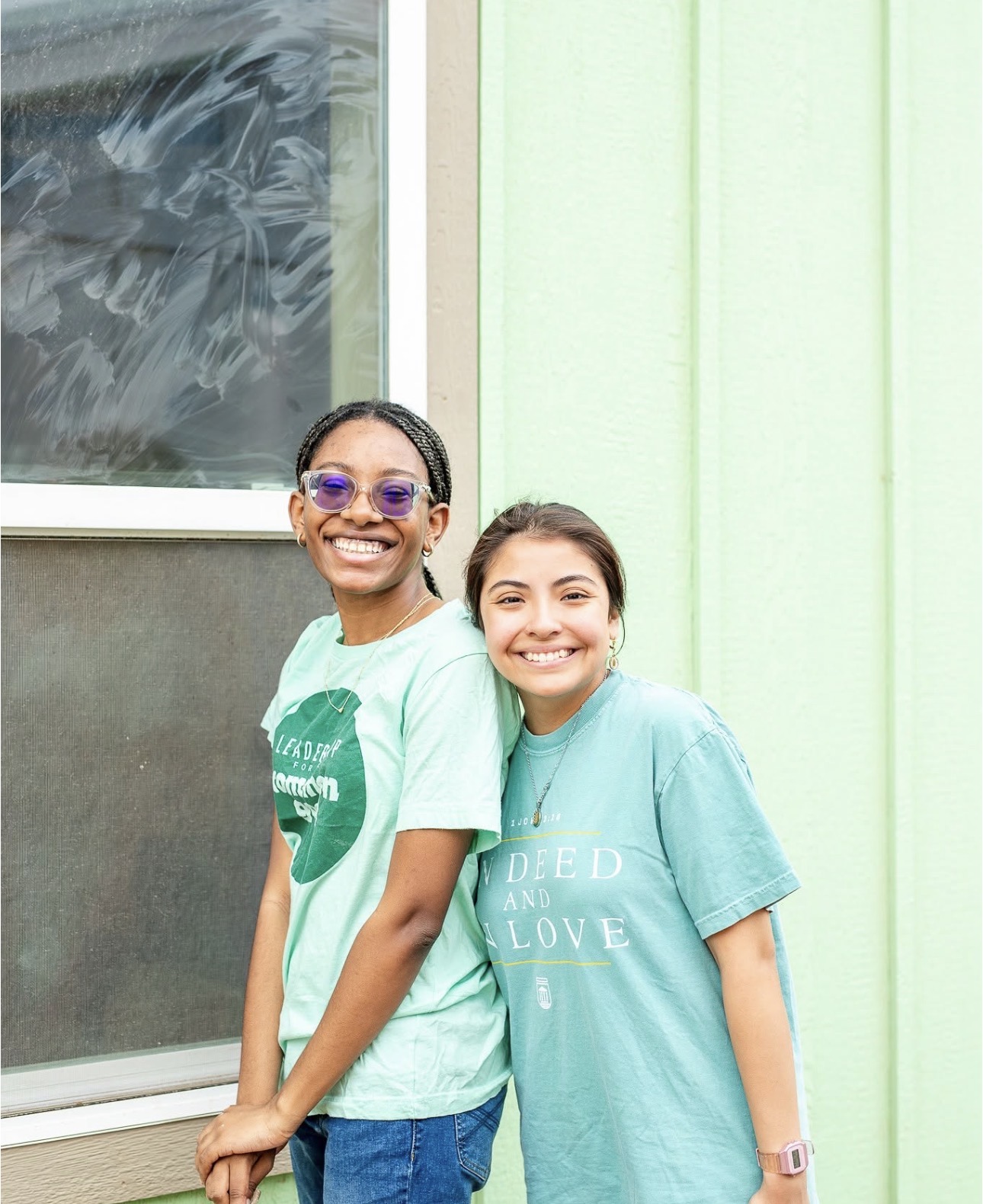 Two students in front of a colorful house during a service project.
